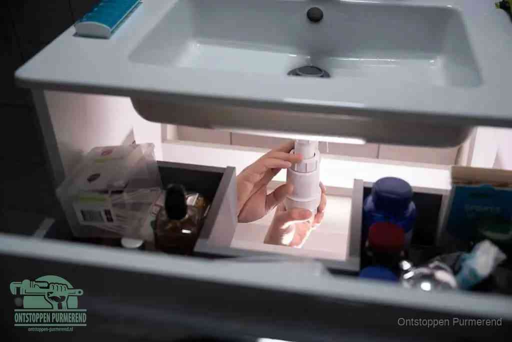 Een pompfles met zeep boven een wastafel, de heet water en afwasmiddel-methode om een vetprop in de afvoer los te maken in Purmerend