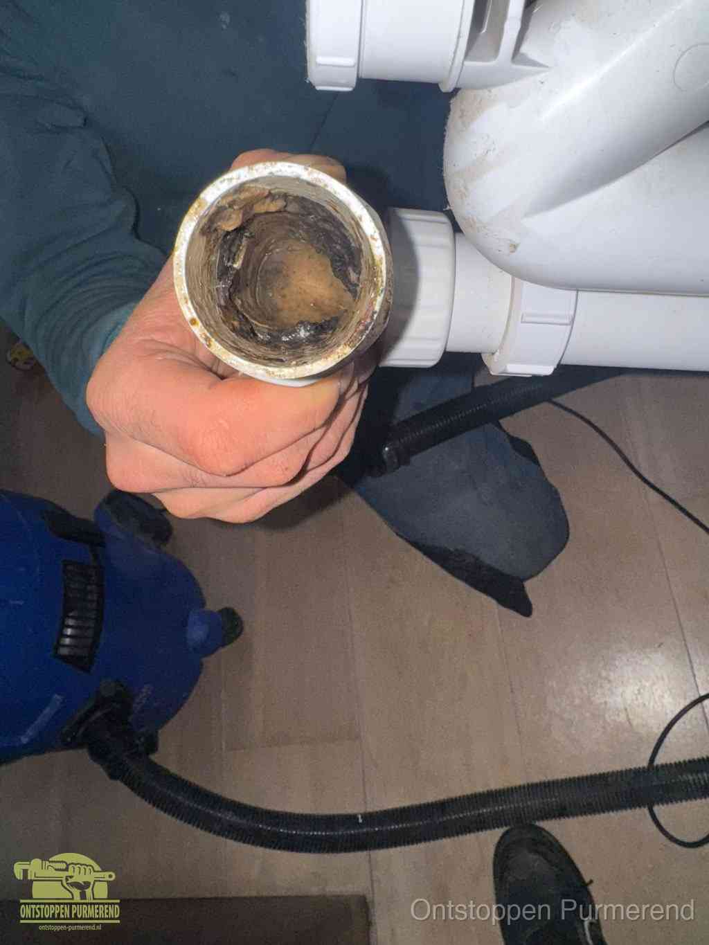 Een losgekoppelde afvoerbuis die van binnen volledig is dichtgeslibd met vet en aanslag, de meest voorkomende oorzaak van een verstopte gootsteen in Purmerend
