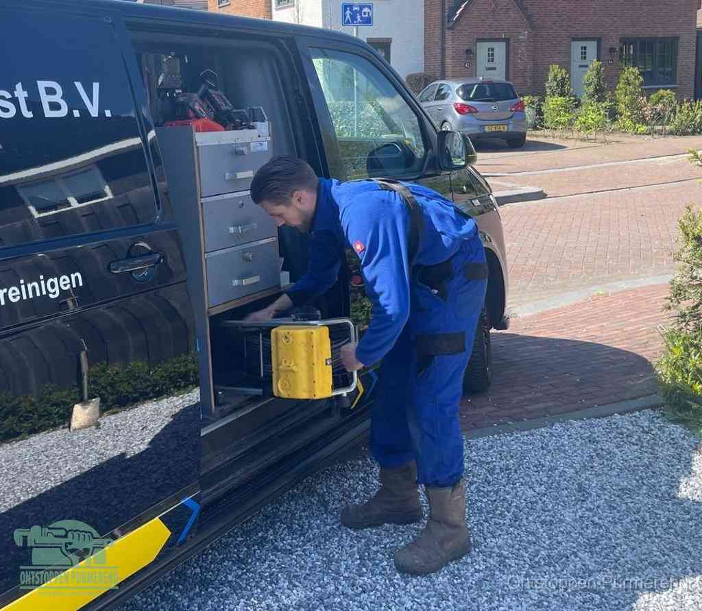 Een monteur pakt buiten op de oprit gereedschap uit de bedrijfsbus, het moment om een professional in te schakelen voor een verstopte afvoer in Purmerend