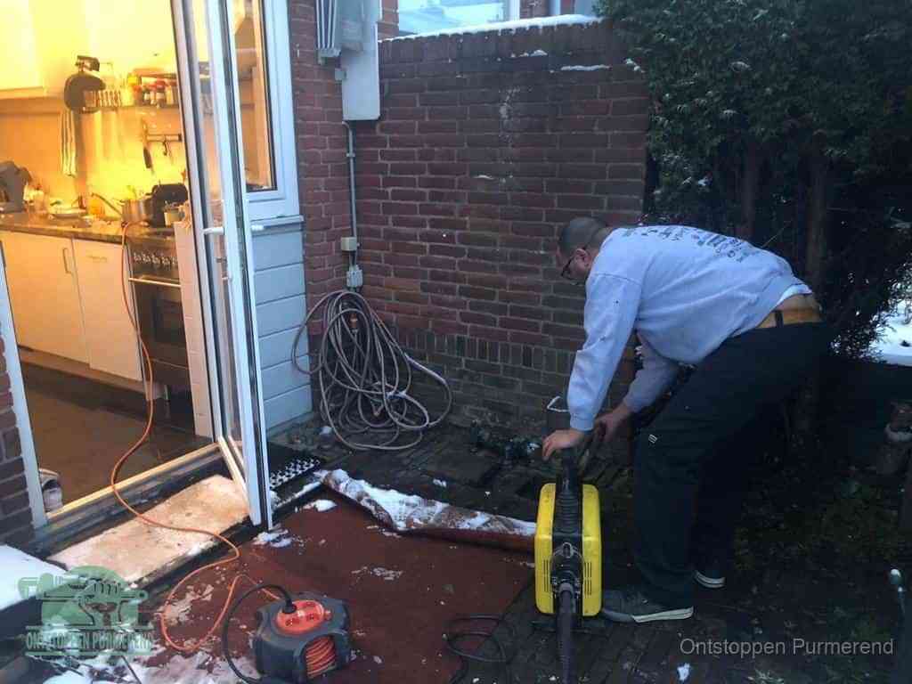Een monteur werkt buiten bij een open riool-/grondput met een elektrische ontstoppingsmachine om een verborgen afvoerprobleem op te sporen in Purmerend