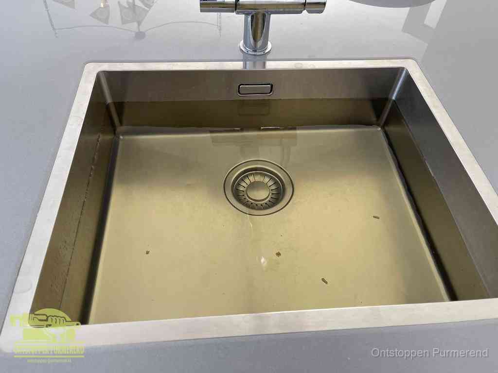 Stilstaand water in een rvs spoelbak dat niet wegloopt, een duidelijk signaal van een gootsteenverstopping in Purmerend
