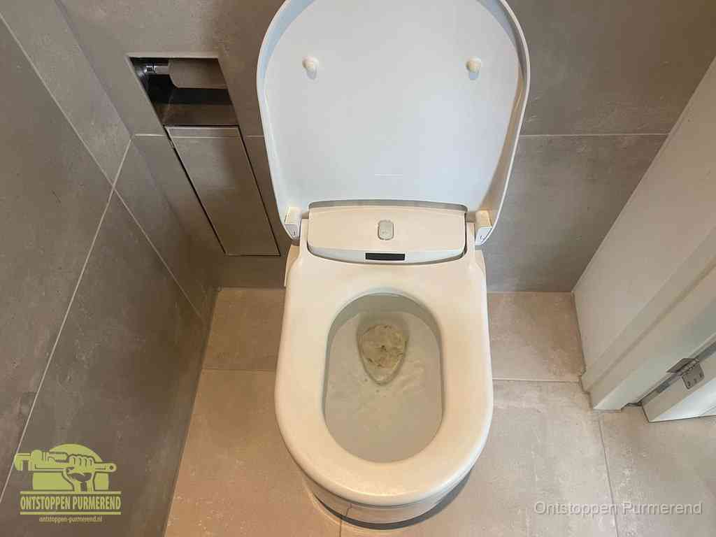 Een wit hangtoilet waarin een prop wc-papier op het water blijft drijven, een duidelijk signaal van een verstopte wc in Purmerend