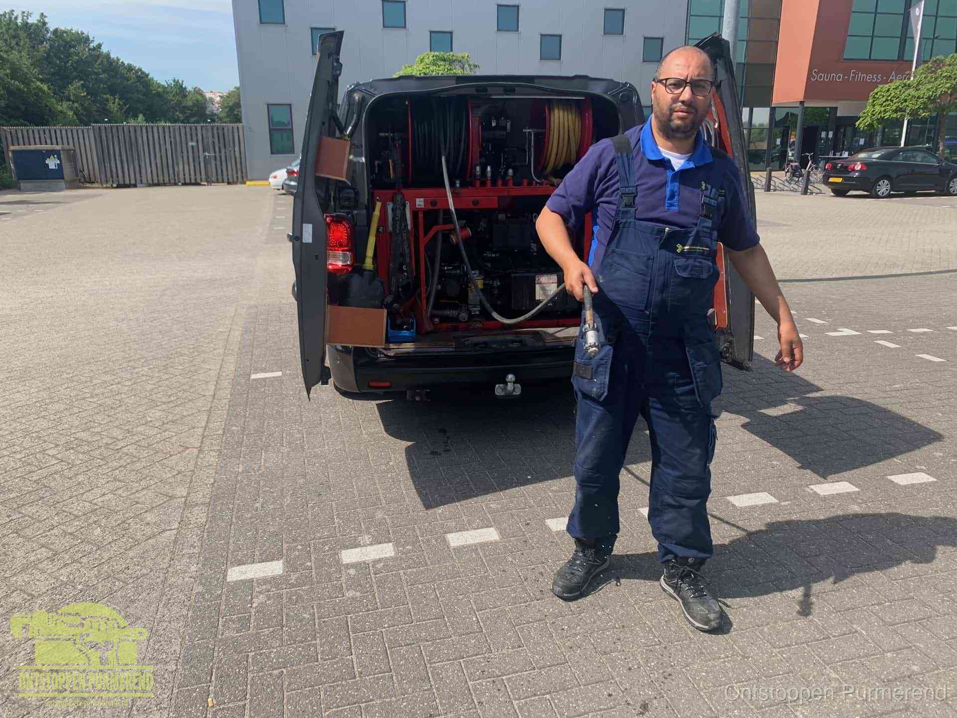 Een monteur bij zijn bestelbus met een hogedruk- en rioolreinigingsunit, klaar om de oorzaak van terugkerende wc-verstoppingen aan te pakken in Purmerend