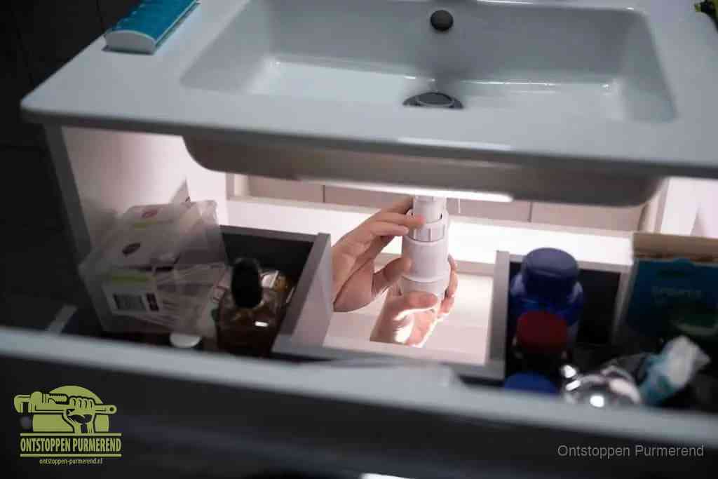 Een pompfles met zeep boven een wastafel in de toiletruimte, de warm water en afwasmiddel-methode om de wc te ontstoppen in Purmerend
