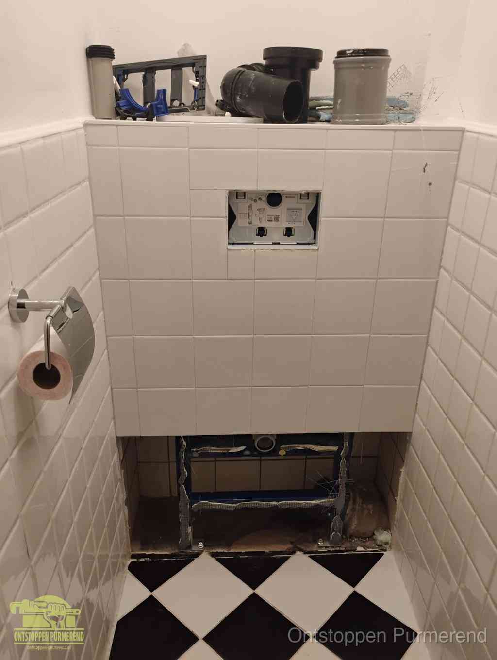 Een toiletruimte waar het hangtoilet en de inbouwreservoir-onderdelen zijn vrijgelegd voor onderhoud, periodiek nazicht voorkomt een wc-verstopping in Purmerend