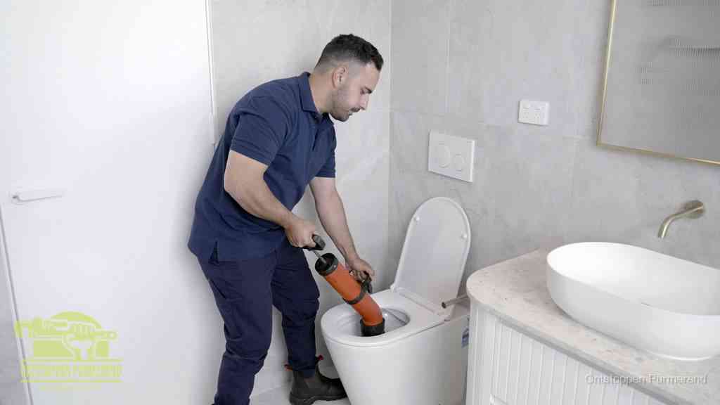 Een monteur gebruikt een handmatige perspomp (toiletontstopper) op een wandcloset tijdens het professioneel wc ontstoppen in Purmerend