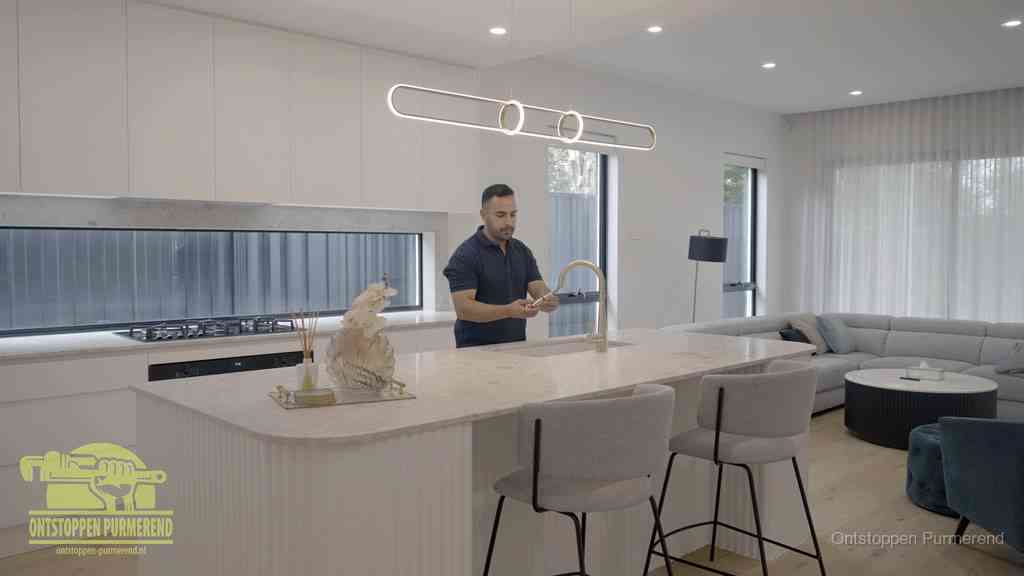 Een bewoner bij de keukenspoelbak die zelf aan de slag gaat met een verstopte gootsteen in Purmerend